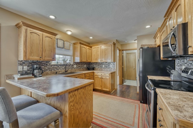 kitchen with a breakfast bar, a sink, tasteful backsplash, stainless steel appliances, and a peninsula