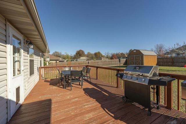 wooden terrace featuring an outbuilding, a grill, a storage unit, and a fenced backyard