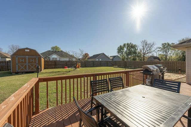 deck featuring a lawn, outdoor dining area, a fenced backyard, an outbuilding, and a storage unit