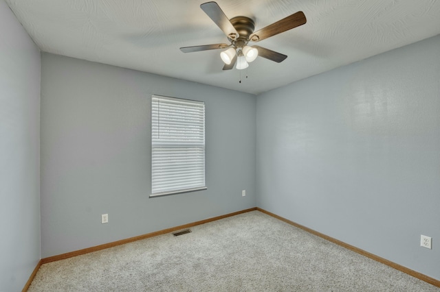 carpeted empty room with visible vents, baseboards, and ceiling fan