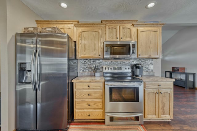 kitchen with light brown cabinets, dark wood finished floors, stainless steel appliances, light countertops, and decorative backsplash