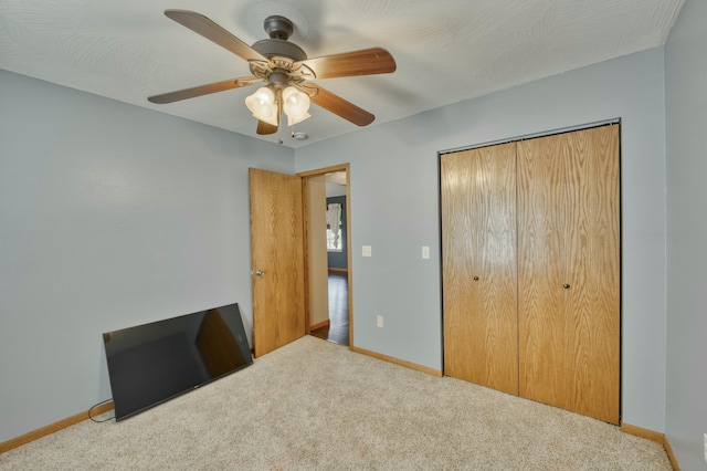 unfurnished bedroom featuring a closet, carpet flooring, a ceiling fan, and baseboards