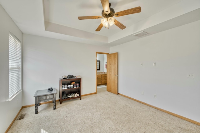 interior space with visible vents, light colored carpet, baseboards, and a tray ceiling