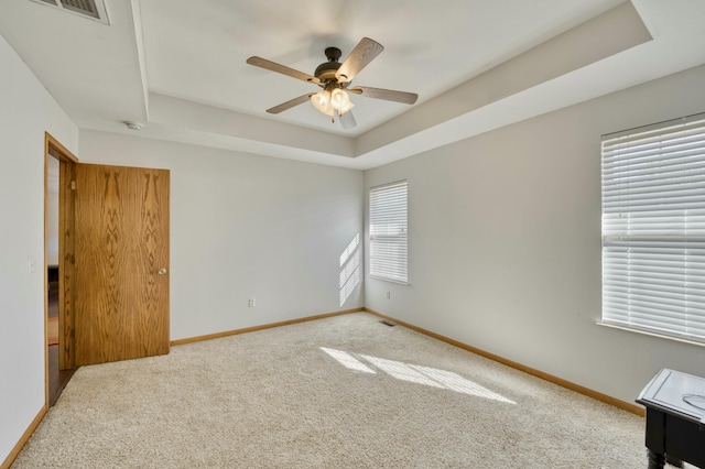 spare room featuring carpet, a raised ceiling, baseboards, and visible vents