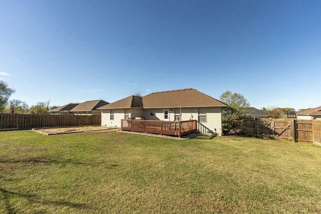 rear view of house featuring a yard, a wooden deck, and a fenced backyard