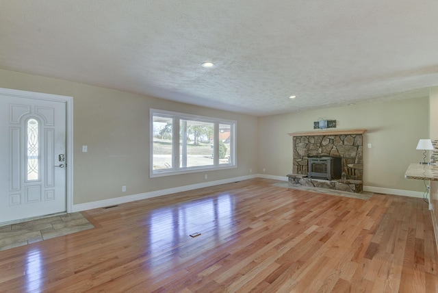 unfurnished living room with visible vents, light wood-style flooring, a textured ceiling, and baseboards