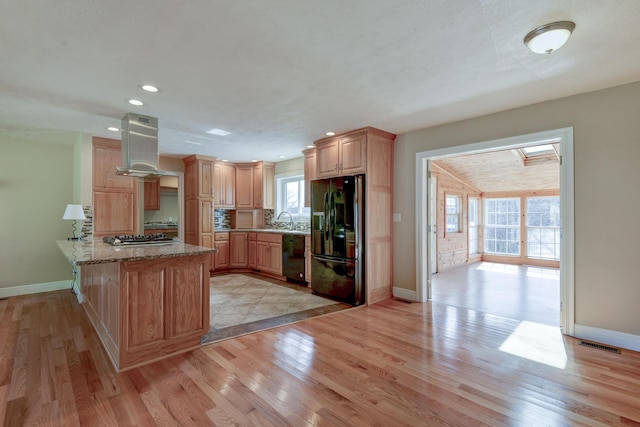 kitchen featuring visible vents, wall chimney range hood, a peninsula, light wood-style floors, and black appliances