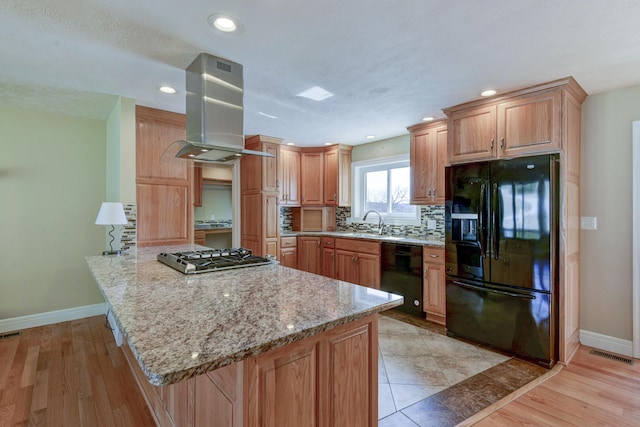 kitchen with tasteful backsplash, visible vents, range hood, a peninsula, and black appliances