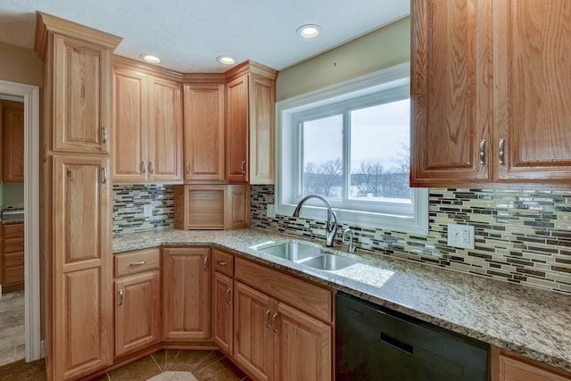 kitchen with black dishwasher, light stone countertops, light tile patterned floors, and a sink