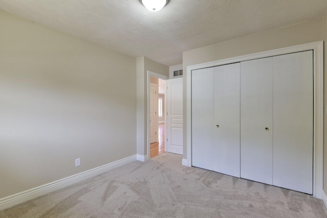 unfurnished bedroom featuring visible vents, baseboards, carpet flooring, a closet, and a textured ceiling