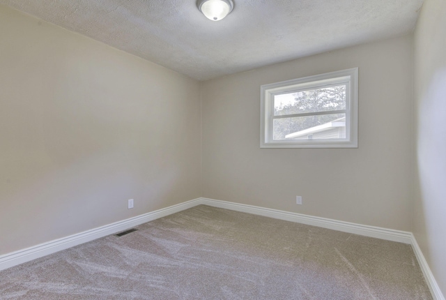 unfurnished room with visible vents, a textured ceiling, baseboards, and carpet floors