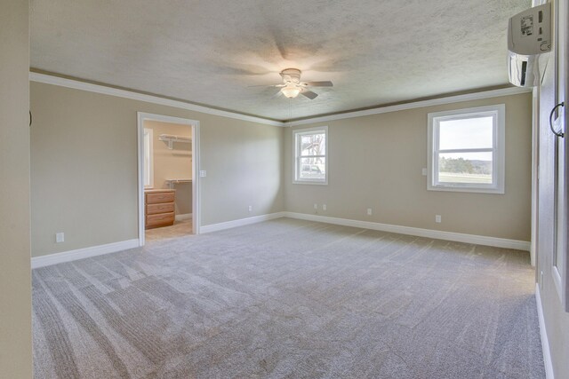 unfurnished bedroom with a walk in closet, light carpet, a textured ceiling, crown molding, and baseboards