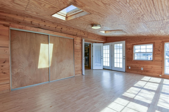 interior space featuring wooden walls, wooden ceiling, a skylight, and wood finished floors