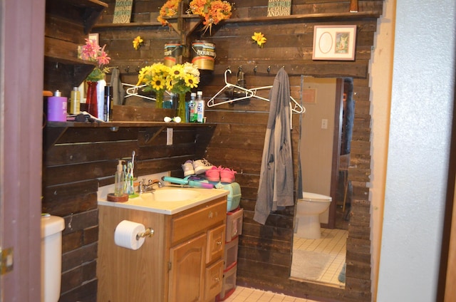 bathroom with tile patterned floors, wooden walls, toilet, and vanity