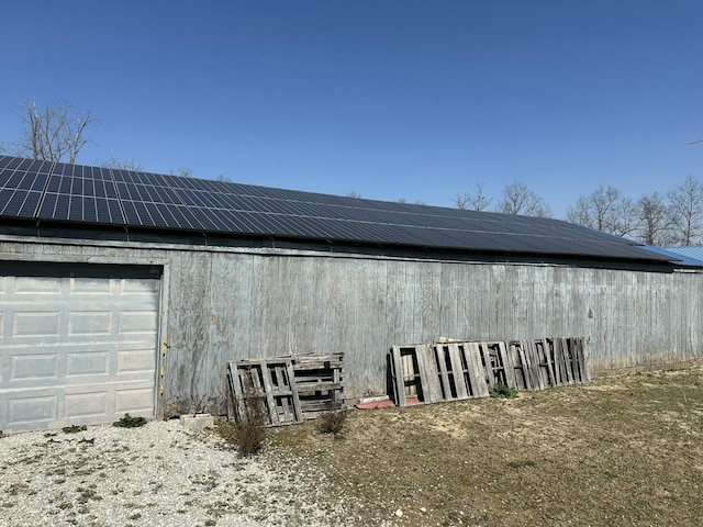 exterior space with an outbuilding, a garage, and roof mounted solar panels