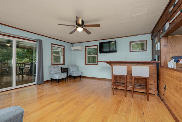 interior space with light wood finished floors, a wall mounted AC, ceiling fan, ornamental molding, and a dry bar