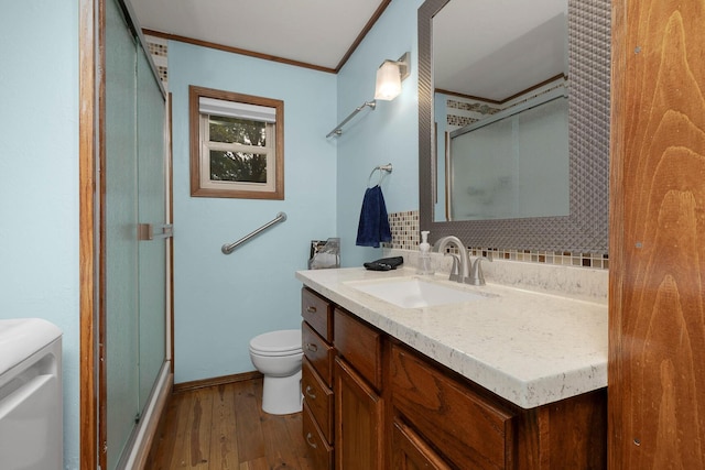 full bath featuring toilet, ornamental molding, a stall shower, wood finished floors, and vanity