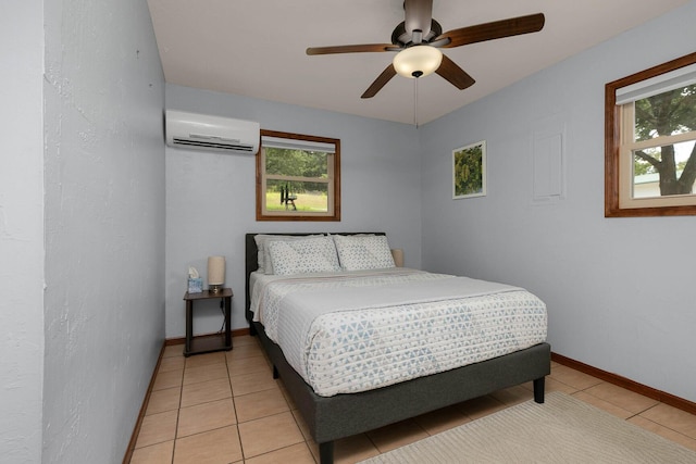 bedroom with baseboards, an AC wall unit, light tile patterned flooring, and a ceiling fan