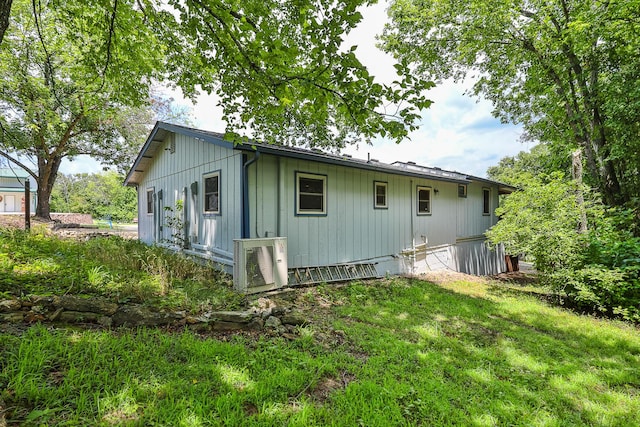 back of property featuring a lawn and ac unit