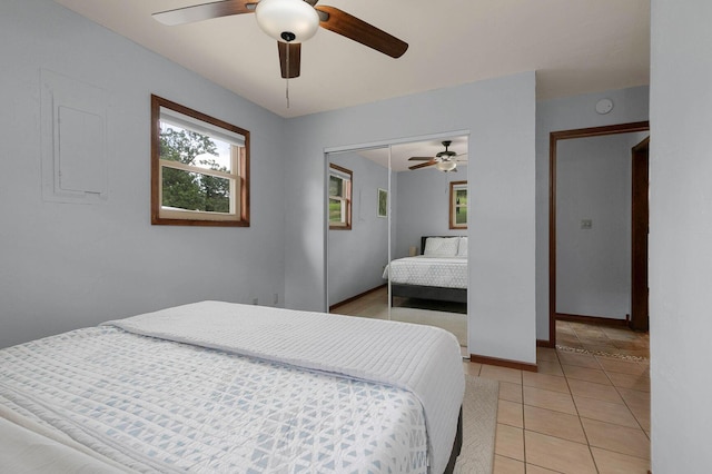 bedroom with light tile patterned flooring, a ceiling fan, a closet, and baseboards