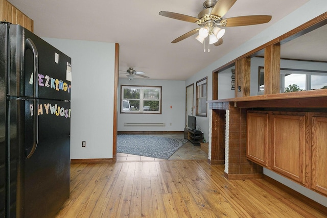 kitchen featuring brown cabinetry, baseboards, a baseboard radiator, freestanding refrigerator, and light wood-style floors