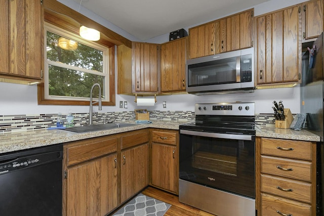 kitchen featuring brown cabinetry, appliances with stainless steel finishes, and a sink