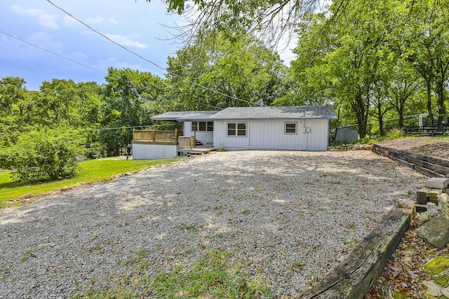 view of front of property with a wooden deck, gravel driveway, and fence