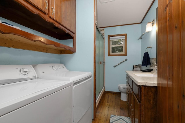 laundry area featuring light wood finished floors, washing machine and dryer, ornamental molding, laundry area, and a sink