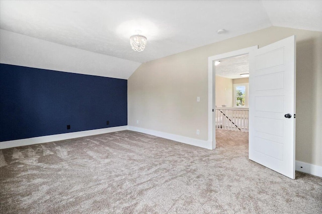 interior space with a chandelier, carpet flooring, baseboards, and lofted ceiling