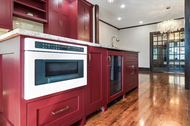 kitchen with crown molding, recessed lighting, wood finished floors, white oven, and a sink