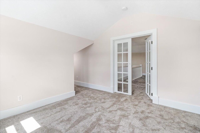 unfurnished room with carpet floors, french doors, baseboards, and vaulted ceiling