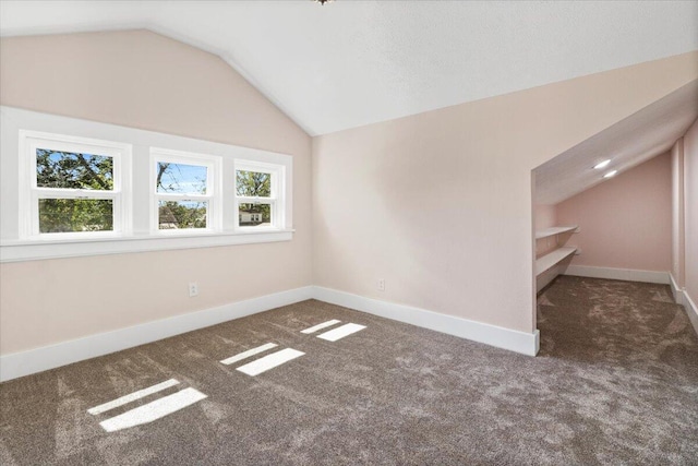 interior space with vaulted ceiling, carpet flooring, and baseboards