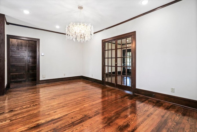 unfurnished room featuring ornamental molding, wood finished floors, recessed lighting, an inviting chandelier, and baseboards