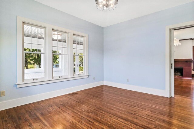 empty room with visible vents, baseboards, dark wood-style flooring, and a chandelier