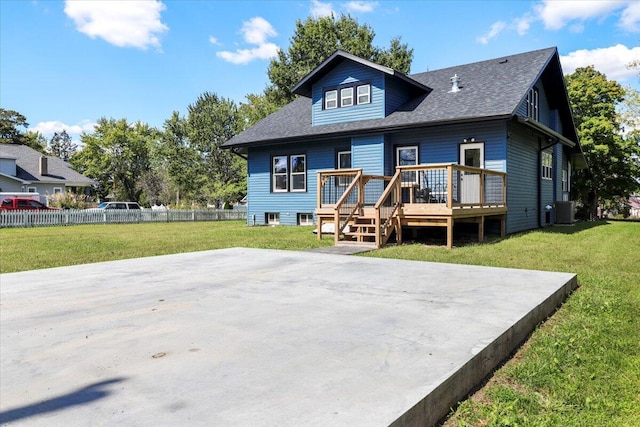 rear view of property with central AC unit, a wooden deck, a yard, and fence