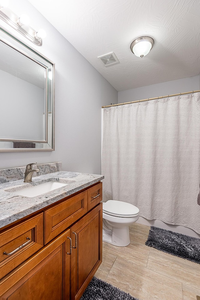 full bath with visible vents, toilet, wood finished floors, and vanity