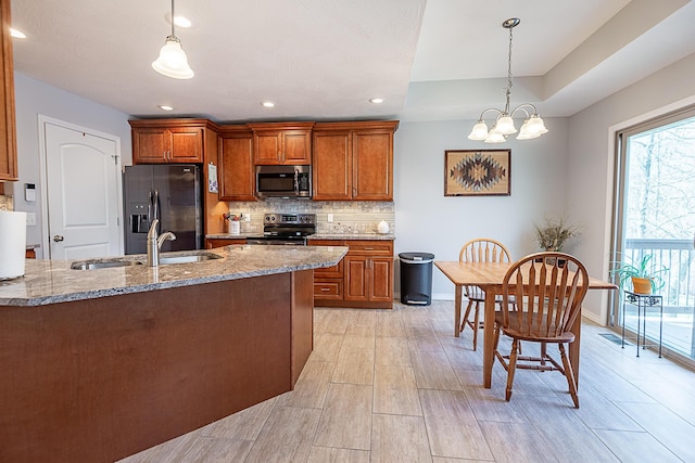 kitchen with light stone countertops, tasteful backsplash, appliances with stainless steel finishes, and brown cabinetry