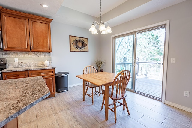 dining room featuring an inviting chandelier, a raised ceiling, and baseboards