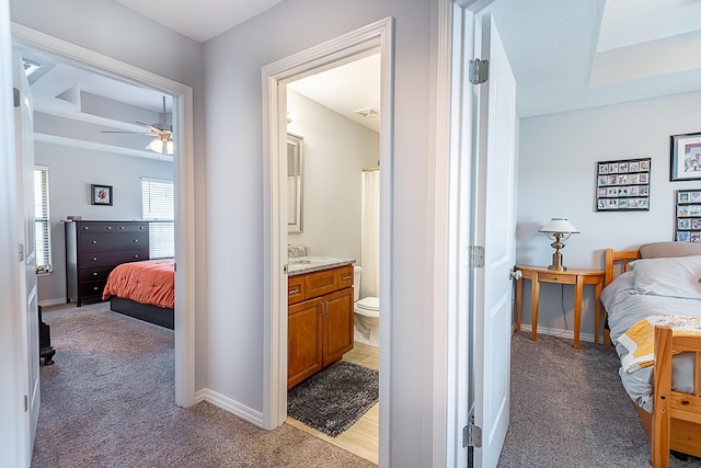 bedroom with light colored carpet, ensuite bath, and baseboards