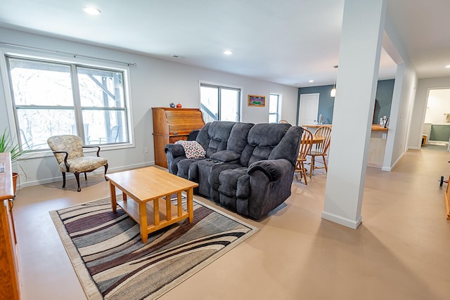 living room with baseboards, a wealth of natural light, and finished concrete floors