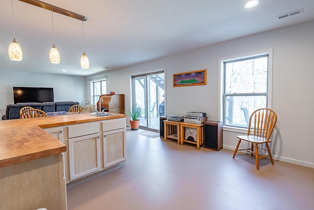 kitchen with visible vents, a sink, wood counters, open floor plan, and concrete flooring