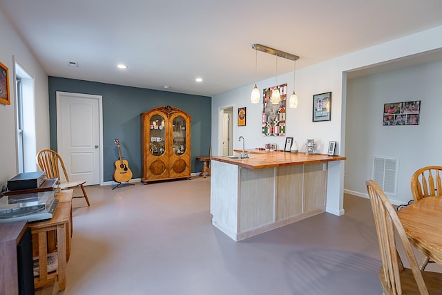 kitchen with visible vents, a peninsula, recessed lighting, butcher block countertops, and concrete flooring