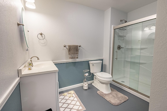 bathroom with vanity, finished concrete flooring, baseboards, a shower stall, and toilet