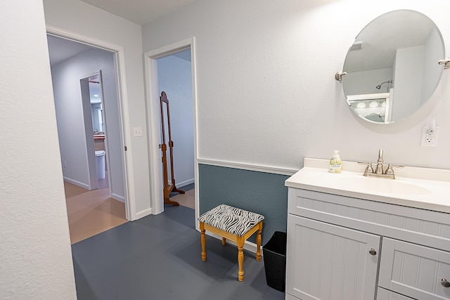 bathroom featuring finished concrete flooring, vanity, and a textured wall