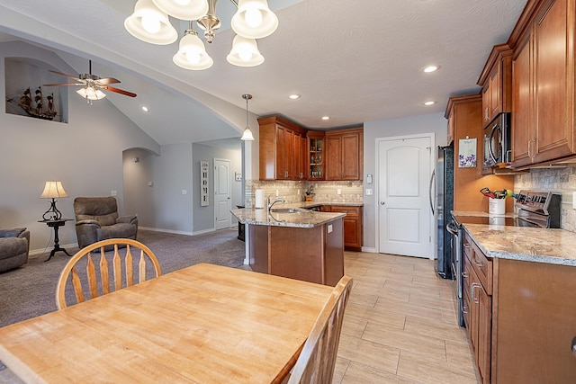 kitchen featuring arched walkways, open floor plan, appliances with stainless steel finishes, and brown cabinets