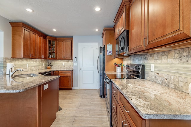 kitchen with brown cabinets, electric stove, a sink, black microwave, and light stone countertops