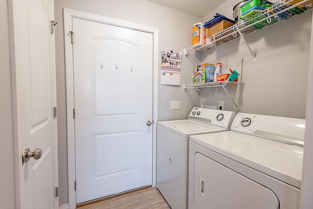 clothes washing area featuring laundry area, washing machine and dryer, and light wood finished floors