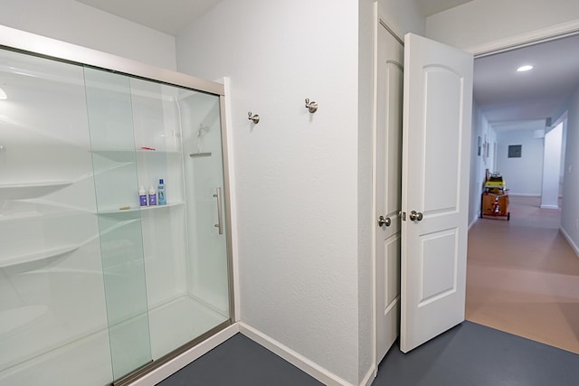 bathroom featuring baseboards, a shower stall, and a textured wall