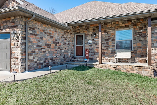 entrance to property featuring a lawn, an attached garage, and roof with shingles