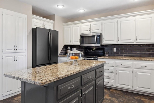 kitchen featuring light stone countertops, a kitchen island, black appliances, white cabinetry, and backsplash